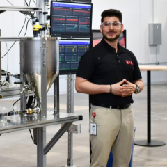 Photo of Rodrigo Perez on the factory floor with computer monitors behind him